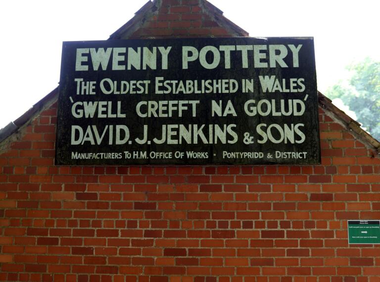 An Ewenny Pottery sign on a brick building.
