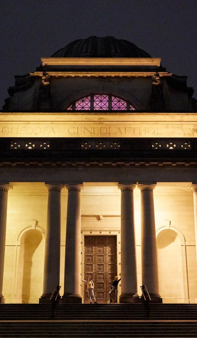 Vue extérieure de l'entrée d'un grand musée, éclairée la nuit.