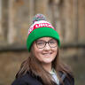 A portrait of a young woman wearing glasses and wearing an 'Urdd' woolly hat