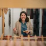 La artista textil galesa Llío James sentada en su telar manual, sonriendo a la cámara.