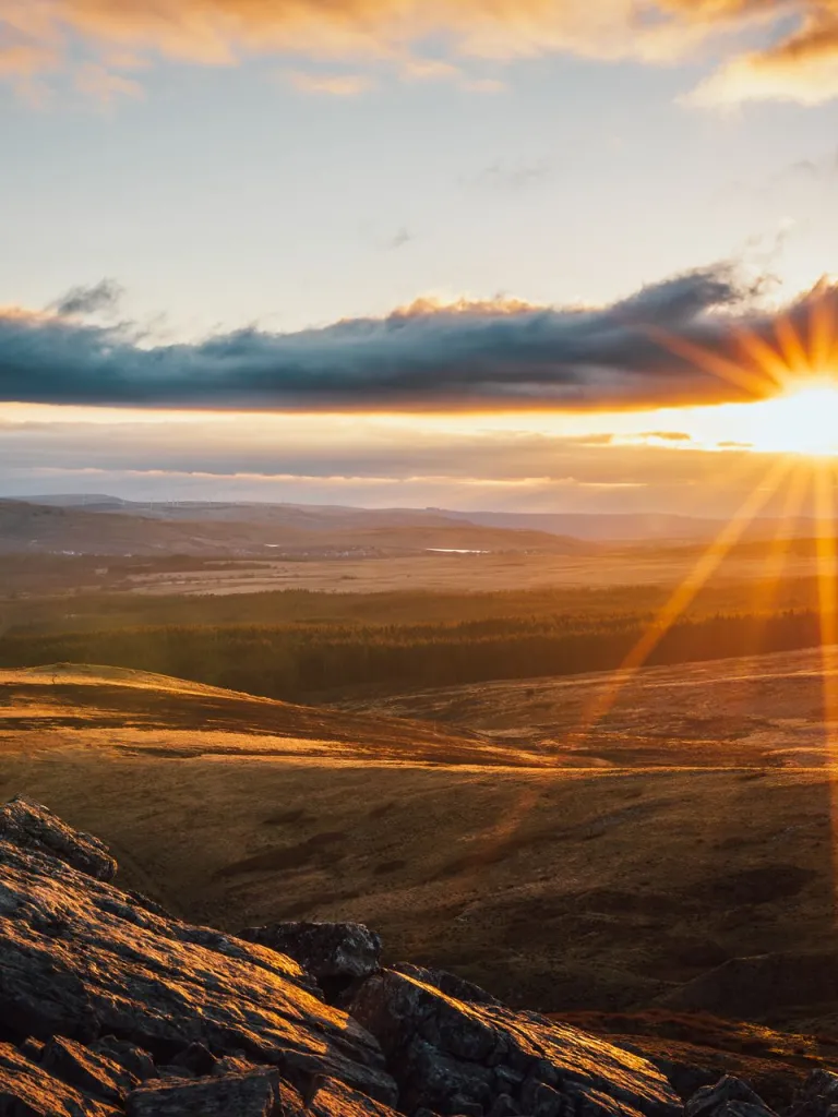 A view of Cribarth, Bannau Brycheiniog with the sun setting in the sky.