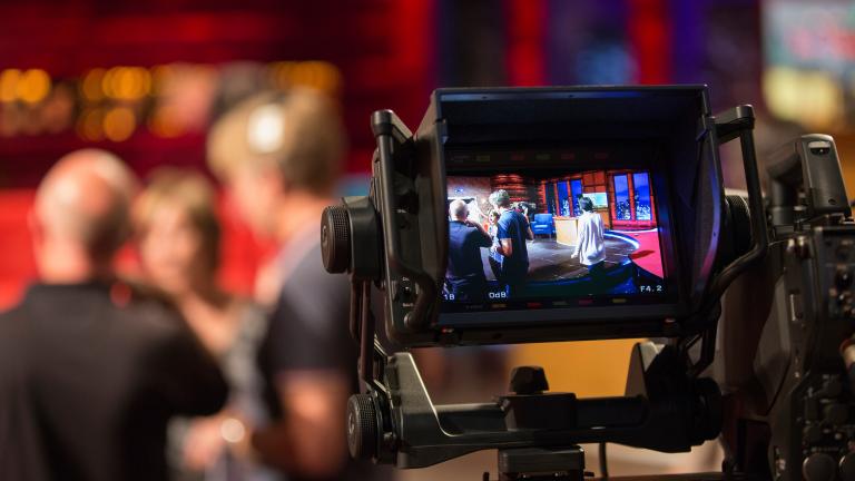 camera screen in focus, showing filming taking place in a television studio 