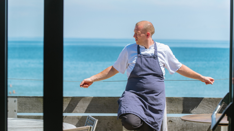 Chef Hywel Griffith en el restaurante Beach House con el mar de fondo.