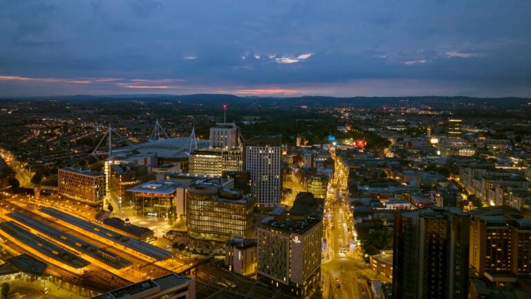 A colourful sunset over a brightly lit, bustling city centre