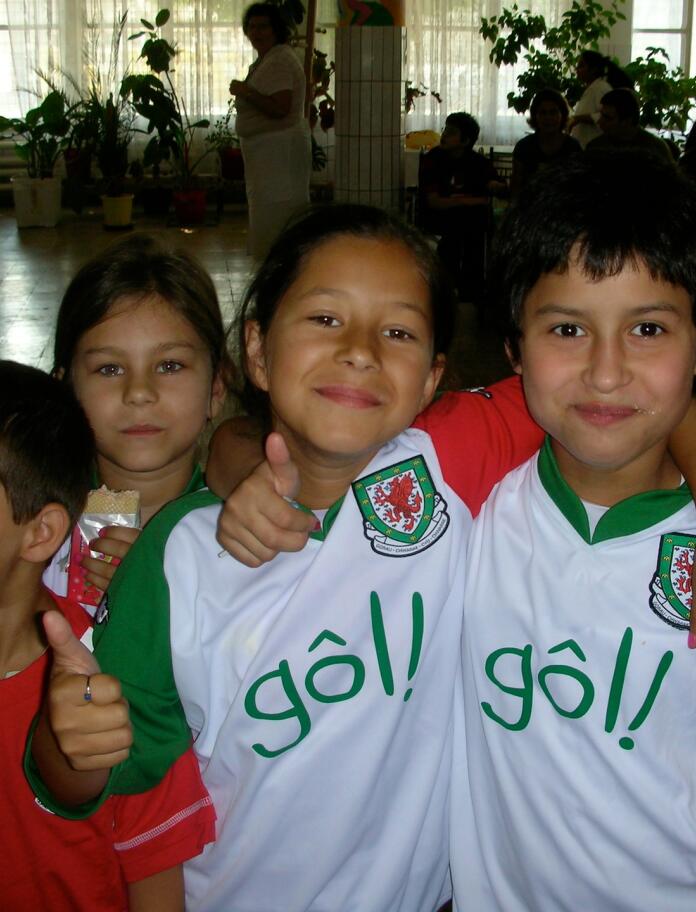A group of smiling children in Gôl Cymru shirts.
