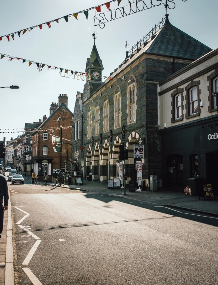 Two people walking down a high street past shop windows.