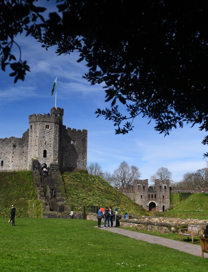 A stone castle on a small hill surrounded by grass.