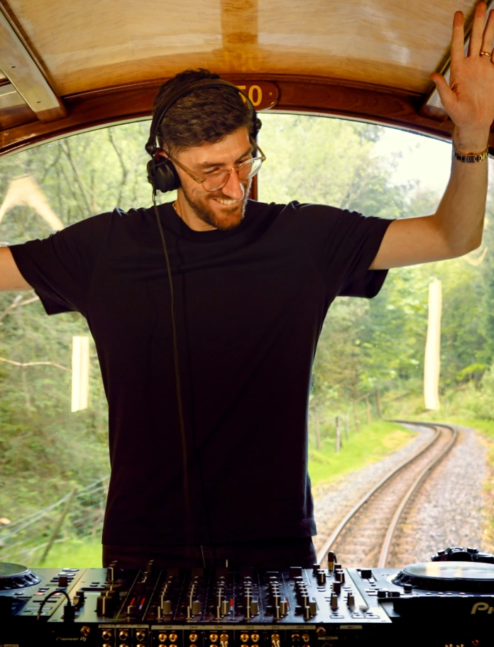 A man with his hands in the air standing at the back of a train.