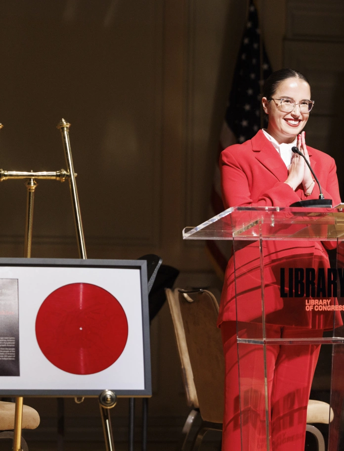 Katie Jenkins speaks at the Library of Congress beside a framed red vinyl edition of Symffoni’r Môr Mawr – A Transatlantic Symphony. 