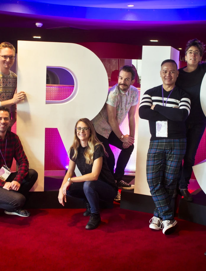 Group of people posing together in front of large illuminated Iris Prize lettering.