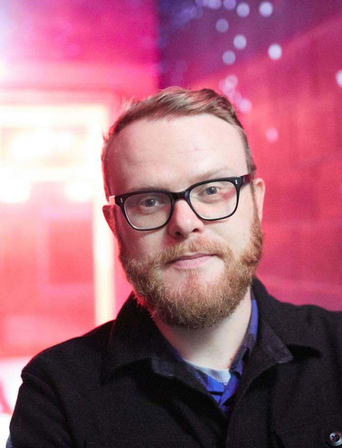 Huw Stephens portrait, in front of a blurred purple lit background
