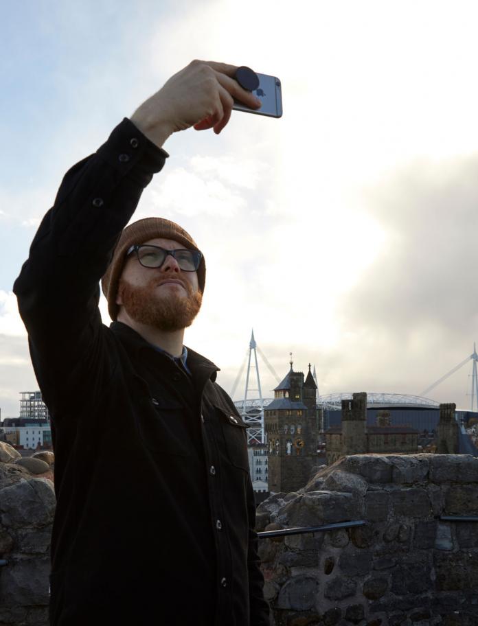 Huw Stephens yn cymryd selfie o flaen Caerdydd dinas o'r Castell