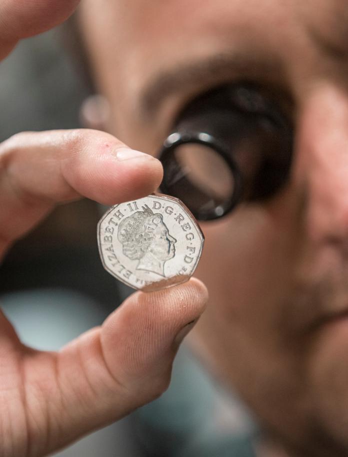  inspección minuciosa de una moneda de cincuenta peniques recién acuñada en Royal Mint, Llantrisant