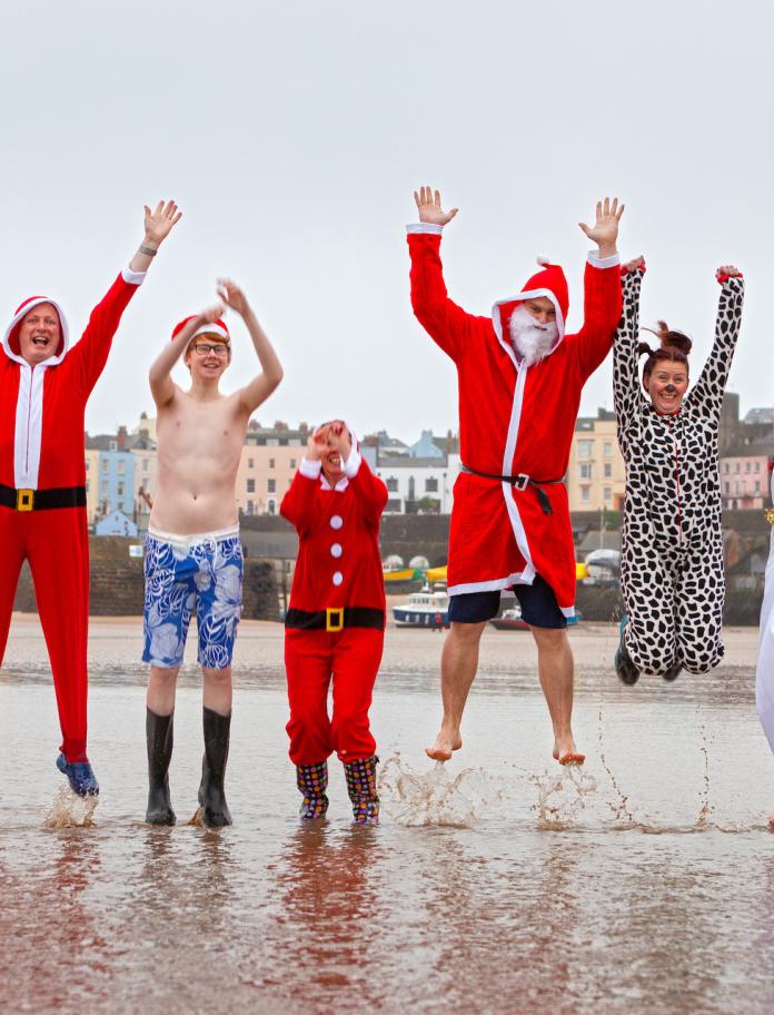 Swimmers in Christmas costumes on beach 