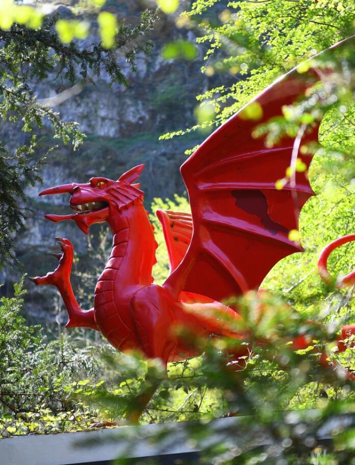 statue of the red Welsh dragon in an outdoor setting surrounded by trees