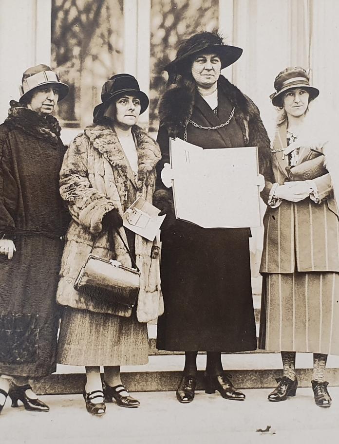 A historical image of four women in the 1920s holding an open petition