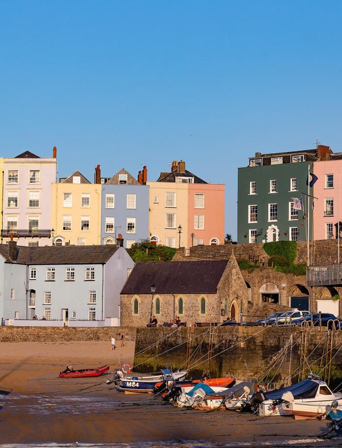 Looking toward Tenby harbour with boats on the sand and colourful houses in the background.