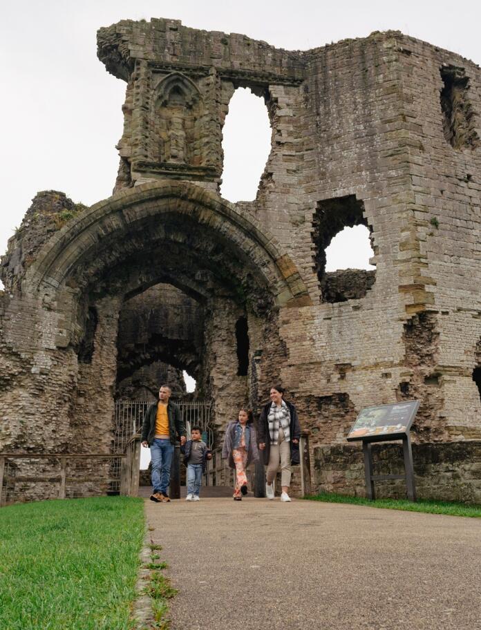 family walking near archway in castle ruin.