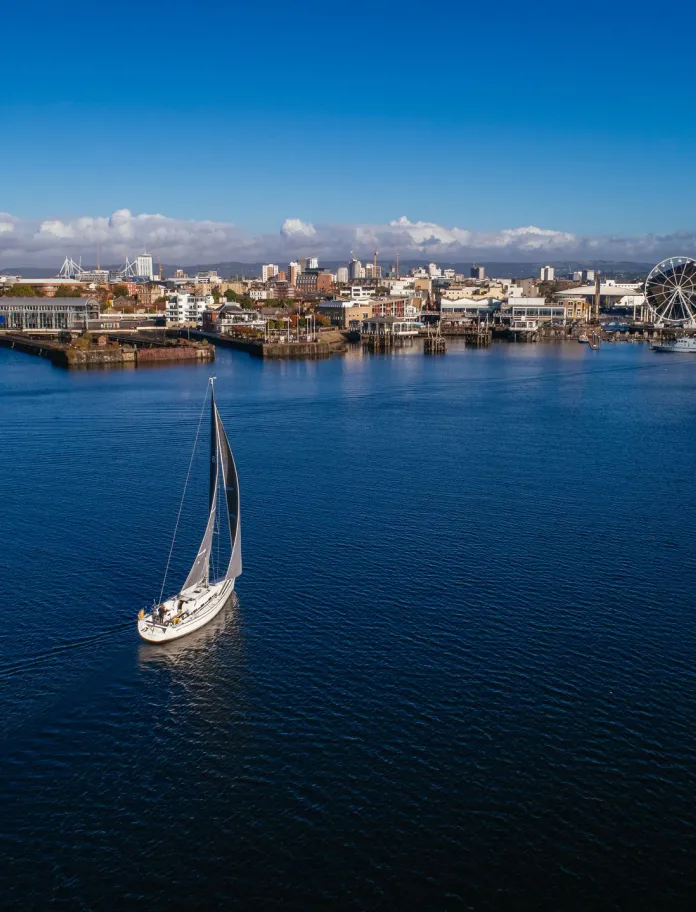 A boat on the water with Cardiff Bay in the background.