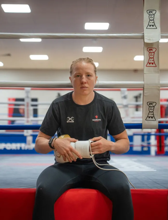 Rosie Eccles sits on the edge of a boxing ring wrapping her hands before training.