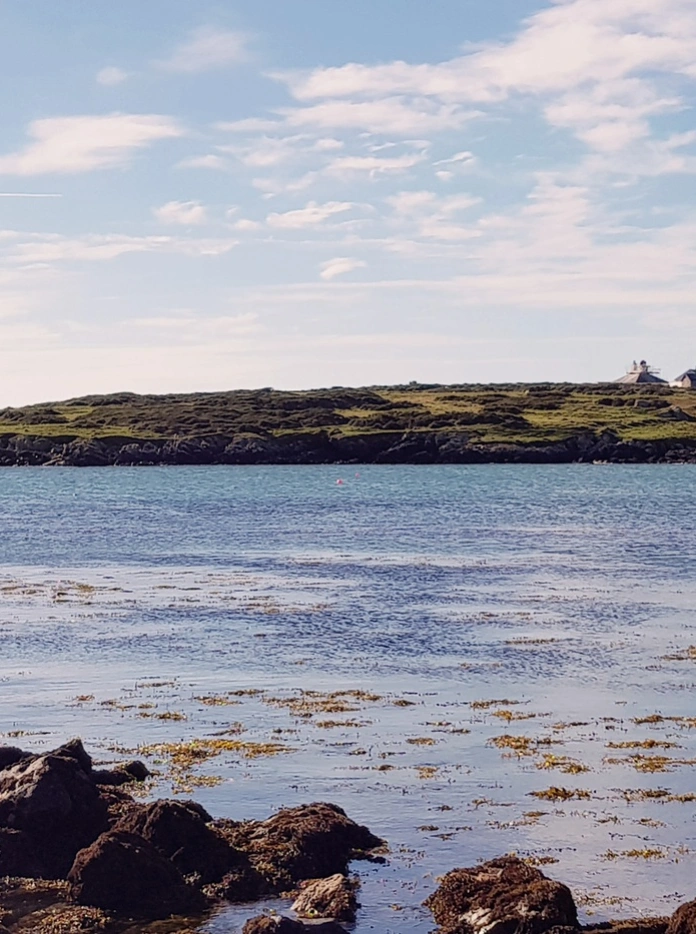 A view of the lighthouse on Bardsey Island from over the sea.