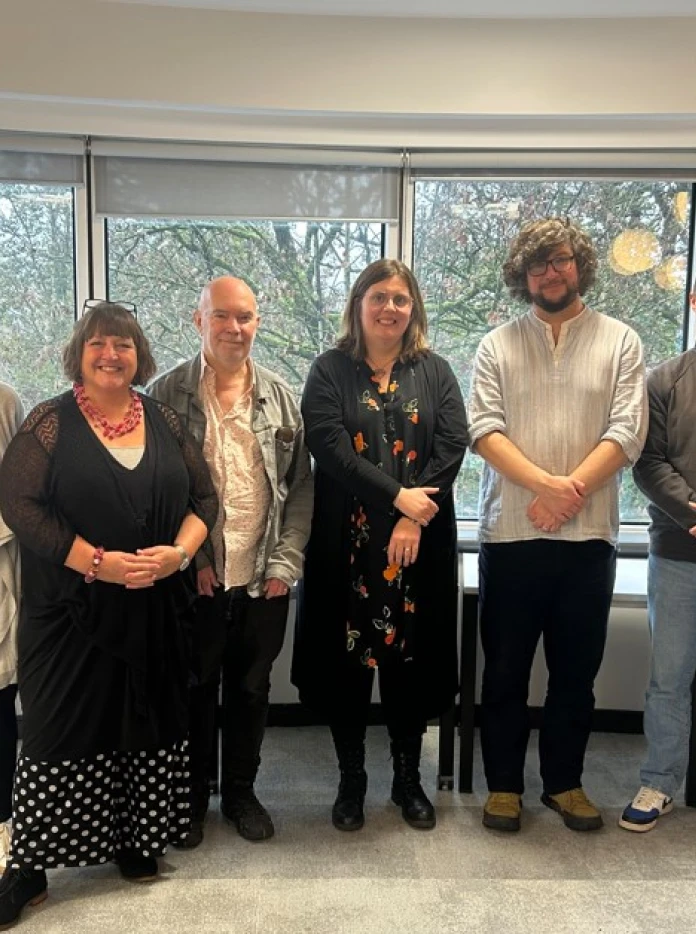 6 people stood smiling at camera