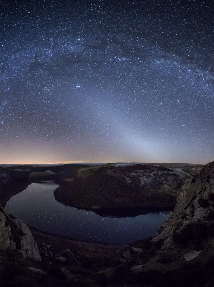 Night shot of a valley with lake and starry skies