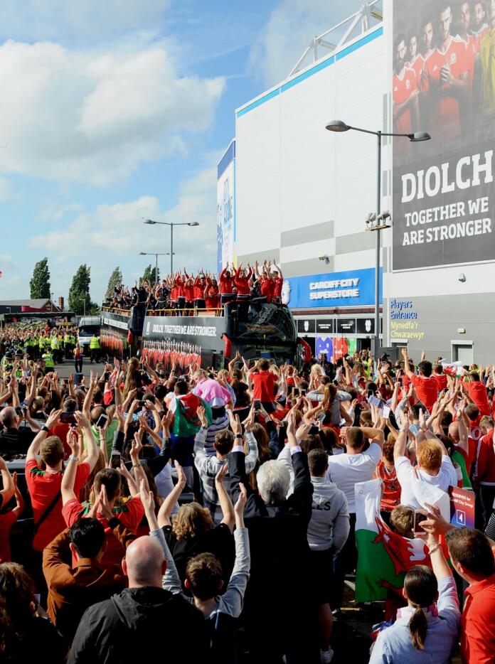 ツアーバスでウェールズサッカーチームを応援する大勢の人々