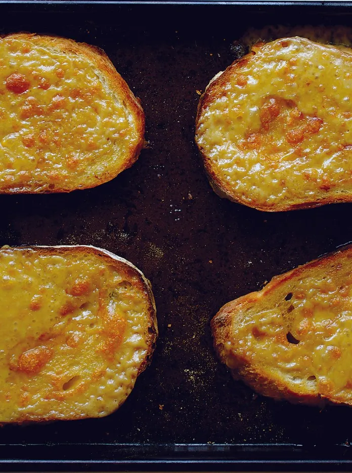A baking tray with slices of freshly grilled Welsh rarebit