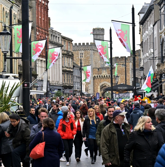 Crowds of people walking through a street with the castle in the background.