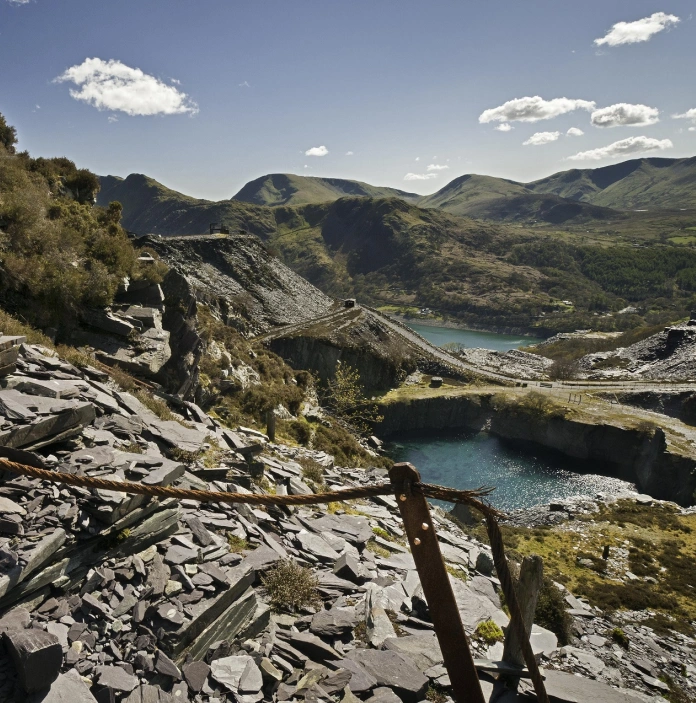 Antigua cantera de pizarra con un lago dentro de montañas verdes.