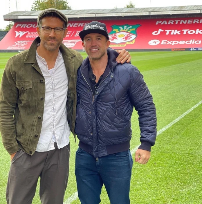 Two men standing on a football pitch facing the camera