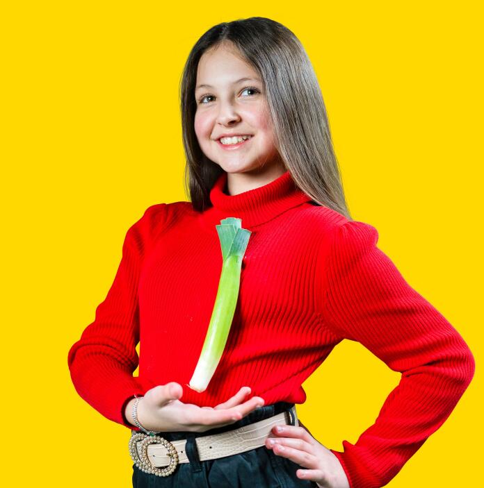 A girl wearing a red jumper with a leek pinned to it