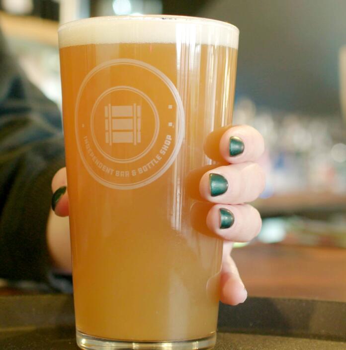 A hand with green fingernails holding a pint of beer