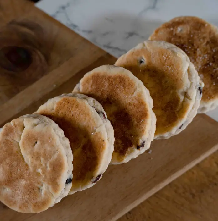 Cinq Welsh cakes alignes sur une planche mi-bois mi-marbre
