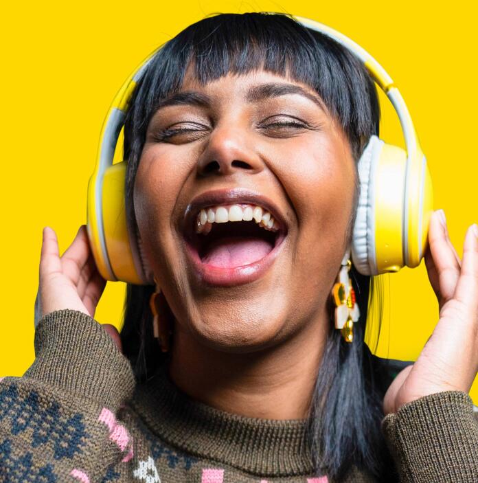 A woman wearing yellow headphones and listening to music