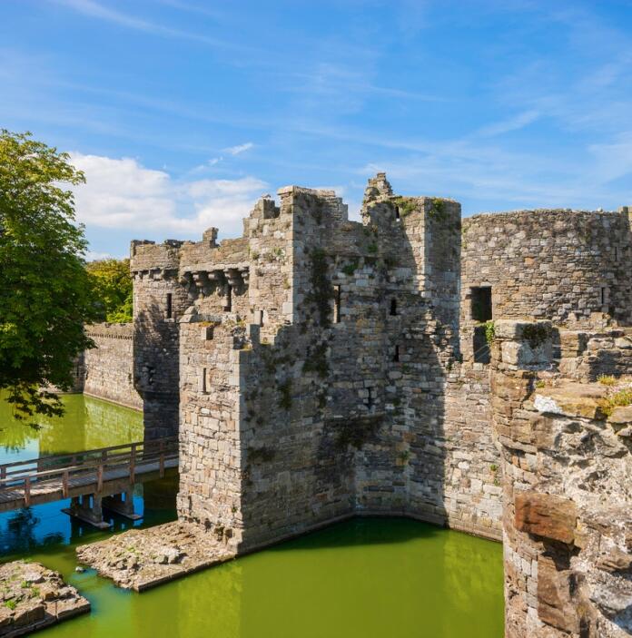 A large old castle with a moat against a blue sky