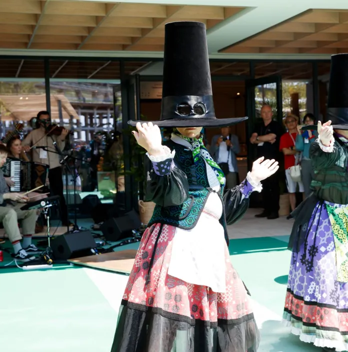 Dancers in traditional Welsh dress with large oversized hats, in mid-performance
