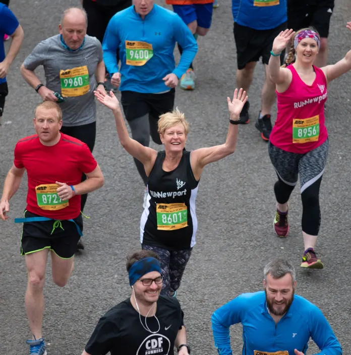 Marathon runners waving at the sky.