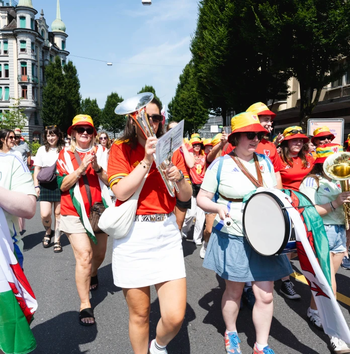 Wales football supporters march through the streets playing brass instruments and drums.