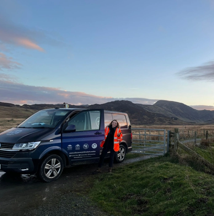 Dark Skies officer Dani Robertson standing next to her van in Eryri National Park