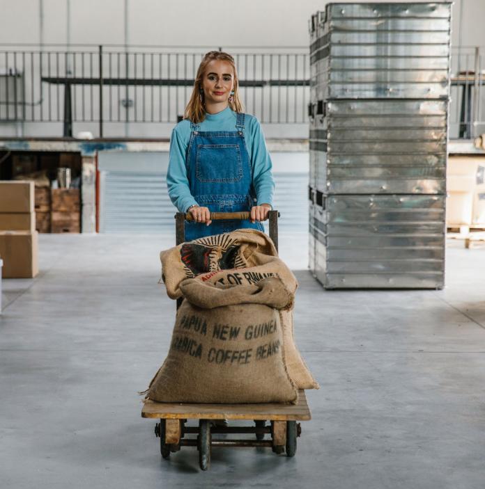 Female transporting coffee beans in hessian bags