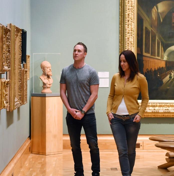 Un homme et une femme regardent des œuvres d'art dans une galerie.