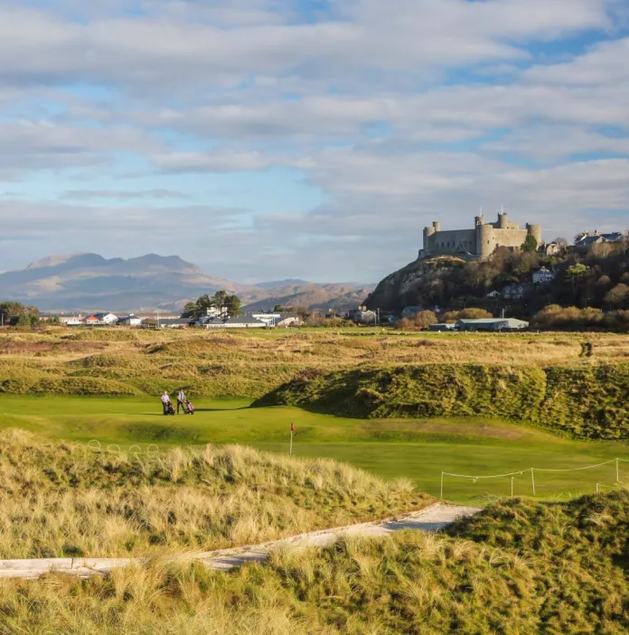 Un campo de golf panorámico con un gran castillo en una colina al fondo