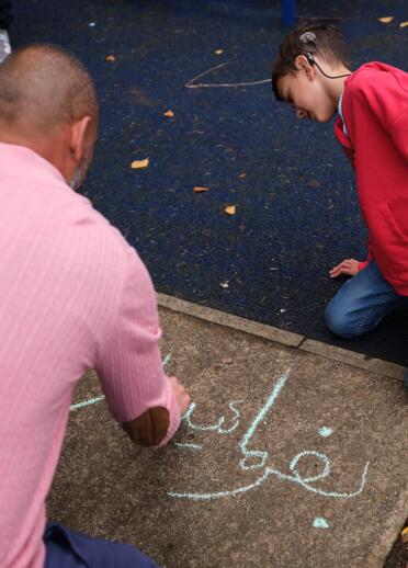 A man and his son drawing in chalk on the pavement