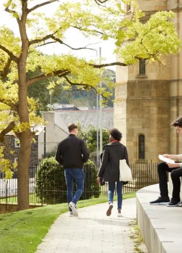 2人が歩いてもう1 人は階段に座ってる、バンガー大学