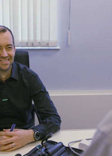 GP Calum Forrester-Paton en su escritorio en la clinica con un paciente