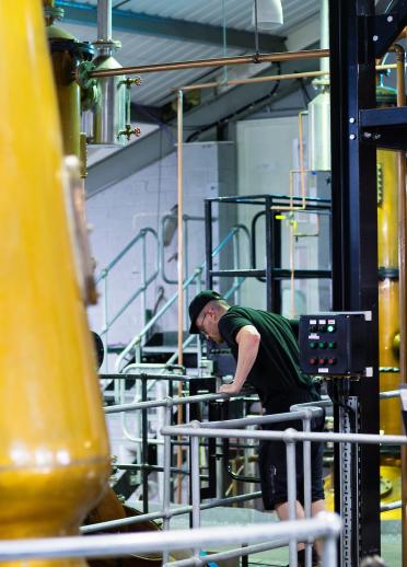 Ein Arbeiter inmitten von Rohren in der Produktionshalle der Penderyn Distillery