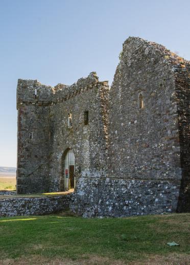 Weobley Castle, Gŵyr, gydag awyr las yn y cefndir.