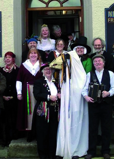 Eine Gruppe von Leute vor einem Pub mit einer Mari Lwyd im Vordergrund.